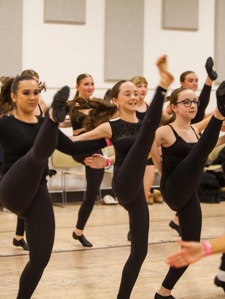 Dancers performing high kicks in studio